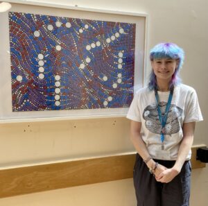 Harri Taylor smiles with her artwork on display