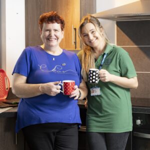 Nicola and Sophie smiling holding mugs of tea